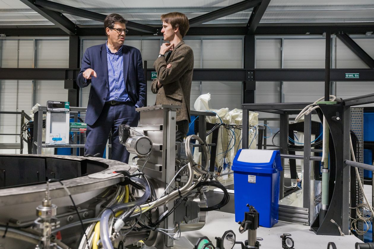Oxford, England-based First Light Fusion co-founders Yiannis Ventikos, left, and Nick Hawker stand atop a machine they’ve developed that can discharge up to 200,000 volts and more than 14 million amperes of power within two microseconds.
